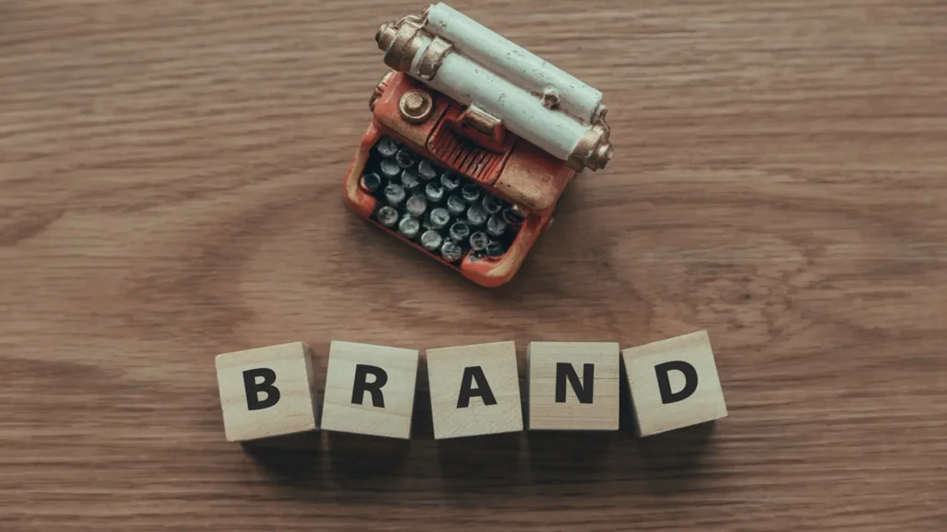 foto com uma máquina de escrever e a palavra "brand" escrita em cubos de letras - Como Escolher os Melhores Tipos de Marca para Seu Negócio?